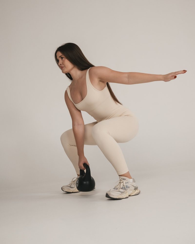 Laura, certified personal trainer and founder of Laura D Studio, performing a kettlebell squat